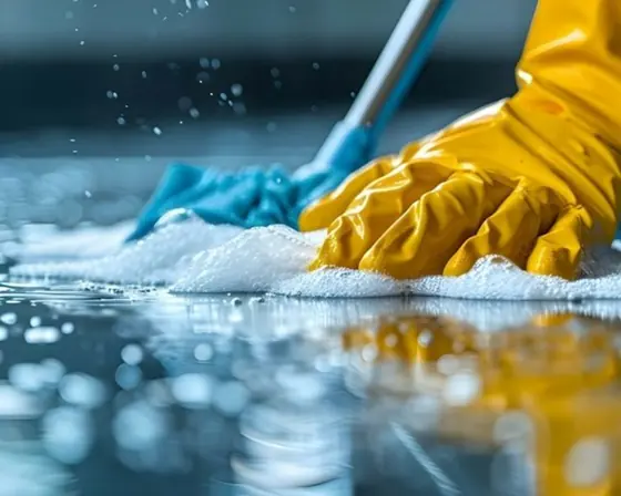 Close view of a gloved hand scrubbing a wet floor until it shines