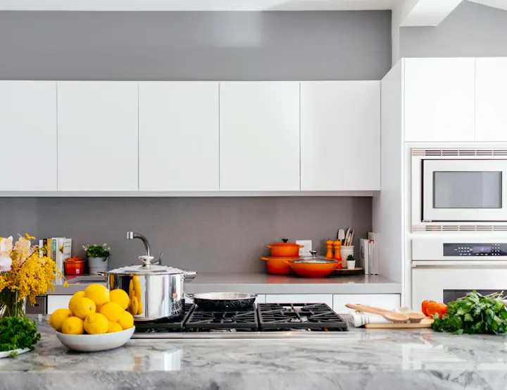 A spotless white kitchen with a marble island