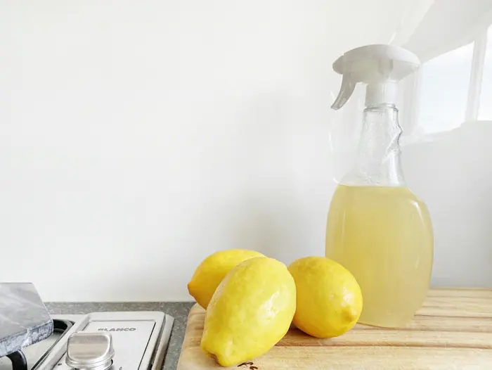 Lemons beside a spray bottle of natural cleaner